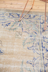 Distressed vintage Oushak carpet detail showing worn texture, faded blue, green, pink floral motifs.