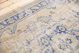 Faded royal blue ornate floral motifs on distressed antique ivory Oushak, pile wear to foundation.