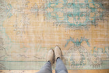 Distressed vintage Oushak rug showing worn pale peach and aqua rococo-style pattern.