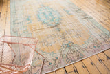 Distressed vintage Oushak carpet with pale peach, aqua blue, and ivory tones.