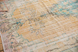 Soft peach and aqua motifs on distressed Oushak rug pile, with visible foundation.