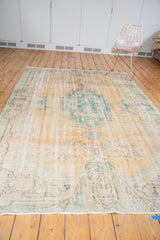 Fringed end of distressed Oushak carpet, with mostly even wear, pale peach and aqua colors.
