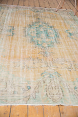 Distressed vintage Oushak rug texture revealing pale peach and aqua patterns.