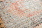 Vintage Oushak rug corner with distressed texture, faded cinnabar red, and visible foundation.