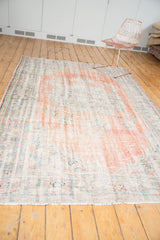 Distressed Oushak rug end, with exposed knot heads, secured fringe, and faded cinnabar tones.