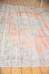 Distressed Oushak rug surface showing worn texture, muted cinnabar, blush, and slate blue.