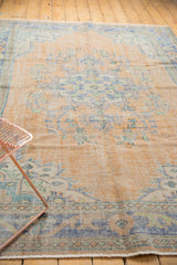 Even wear across faded peach field and royal blue border of vintage Oushak rug corner.
