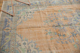 Distressed curvilinear floral motifs in faded peach, royal blue, and mint green.
