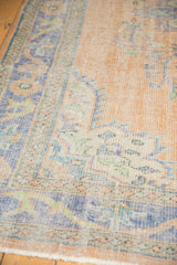 Distressed pile texture of a vintage Oushak rug with faded peach, blue, and mint floral patterns.