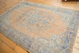 Vintage distressed Oushak corner detail: faded peach field, blue border, floral motifs, even wear.