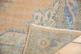 Secured side and faint ivory foundation of the distressed vintage Oushak rug.