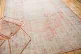 Textural wear on a vintage distressed Turkish Oushak carpet, with soft blush rose and white tones.