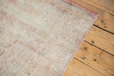 Textured distressed Oushak rug corner with worn pile, exposed knot heads, and blush rose hints.