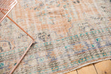 Distressed vintage Oushak carpet: worn pile texture, exposed foundation, and faded apricot, blue motifs.