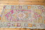 Vintage distressed Oushak rug, oblong medallion with faded purple, tangerine, and soft ivory.