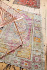 Distressed vintage Oushak rug: intact side selvage, fringed end, and faded jewel-toned motifs.