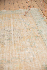 Faded apricot, ivory, and mint floral motifs on distressed vintage Oushak carpet.