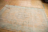 Distressed vintage Oushak carpet with faded apricot and seafoam green designs.