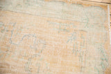 Vintage Oushak rug pile close-up, showing mostly even wear and faded apricot-mint tones.