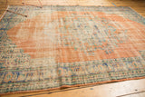 Distressed vintage Oushak rug with exposed foundation, faded blush, blue, and ivory patterns.