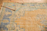 Distressed Oushak carpet close-up, revealing worn pile texture and faded gold, blue, green tones.