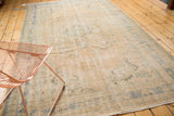 Distressed vintage Oushak carpet corner with light sand colors, visible knot head wear, and fringe.