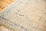 Worn pile texture on a distressed vintage Oushak rug corner with faded blue-green border.