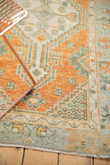 Detailed view of distressed burnt orange and seafoam geometric Oushak rug motifs.