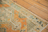 Faded burnt orange and seafoam green border with germinating seed motif on distressed Oushak rug.