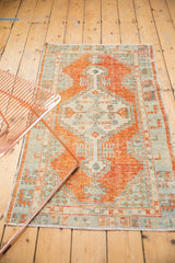 Distressed Oushak rug texture with faded cinnabar red, ivory, and slate blue geometric patterns.