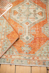 Faded cinnabar, ivory, slate blue Oushak rug with geometric pattern, distressed pile, and fringe.