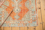 Distressed Oushak rug corner detail, highlighting faded cinnabar red and slate blue geometric patterns.