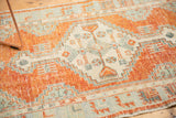 Faded cinnabar and ivory tones on a distressed Oushak rug corner with geometric patterns.