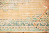 Worn pile texture on distressed apricot Oushak rug with faded blue-green border.