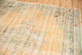Distressed Oushak featuring faded apricot field and Rococo style border in blue and mint green.