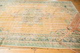 Faded apricot field and Rococo-style border on a distressed vintage Oushak rug.