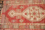 Distressed vintage Oushak runner's cinnabar red field and ivory geometric medallion with wear.