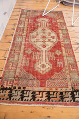 Lower end of the distressed Oushak runner showing bold geometric border and worn fringe.