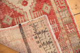 Folded distressed Oushak rug corner, showing reverse foundation, selvedge, and worn red-ivory pile.