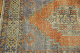 Distressed Oushak rug corner with geometric border and stepped terracotta medallion section.