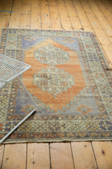 Distressed Oushak rug end with short fringe, muted border, and abrashed terracotta, blue field.