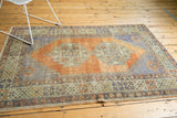 Distressed Oushak rug with abrashed terracotta field, double medallion, and faded blue details.