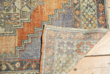 Distressed Oushak rug fold with worn terracotta pile and visible hand-knotted reverse.