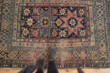 Antique Shirvan rug detail, featuring geometric starburst motifs in blush, navy, and sky blue.