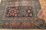 Antique Shirvan rug corner showing geometric starburst, intricate borders in blush red, navy, beige.