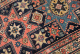 Nuanced starburst arrangements and playful motifs in blush, navy, and sky blue on an antique Shirvan rug.