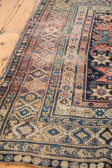 Shirvan rug's nuanced geometric design elements in faded blush, navy, and beige borders.