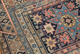 Nuanced geometric starbursts and patterned fills on antique Shirvan rug in blush, navy, and beige.