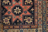 Antique Shirvan rug corner detail: playful stylized figure, geometric stars, and borders in navy, blush, and ivory.
