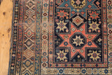 Antique Shirvan rug detail, geometric starbursts, patterned borders in blush red and navy.